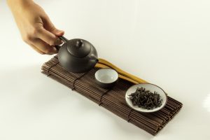 Clay teapot in female hand and other items of Chinese tea ceremony, isolated on white background Clay teapot in female hand and other items of Chinese tea ceremony, isolated on white background